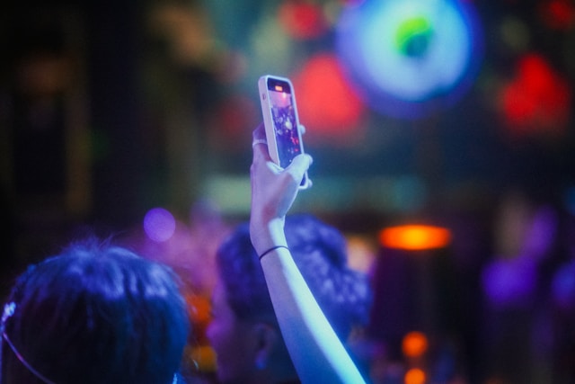 A person in a crowd records a video with a phone.
