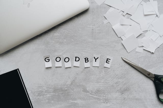 Uma tesoura ao lado de letras recortadas que dizem "Goodbye".