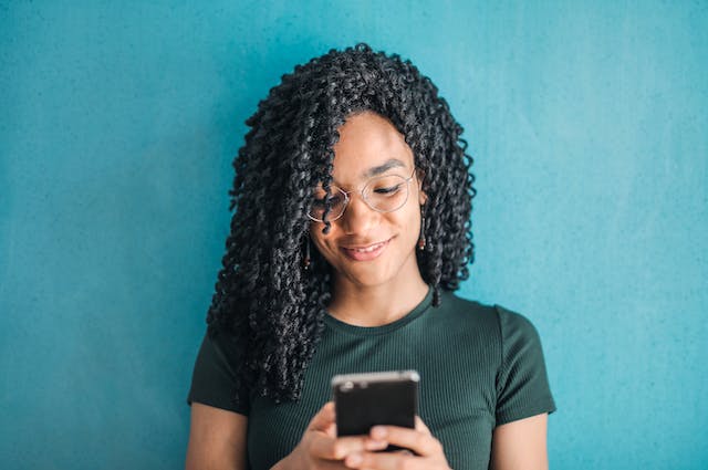 Een vrouw lacht terwijl ze TikTok Stories bekijkt op haar telefoon. 