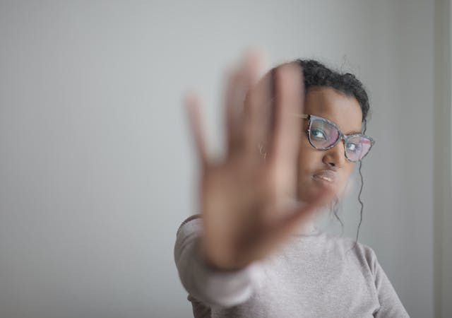 A woman signals stop with her hand. 
