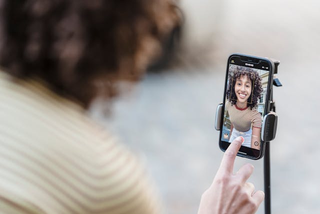 Una donna preme il pulsante di registrazione sul suo telefono per avviare il suo video su TikTok. 