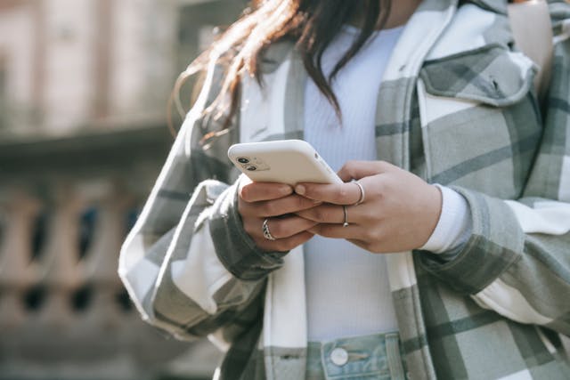 Uma mulher usa as duas mãos para digitar em seu telefone. 