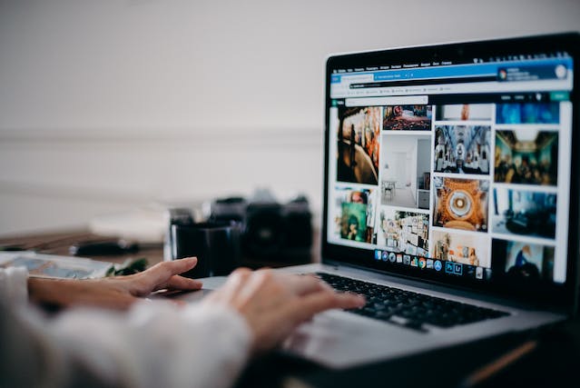 A person scrolls through a grid of videos on a laptop. 
