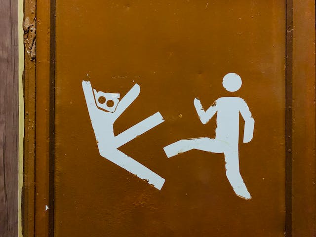 Een tekening op een deur toont een menselijk figuur die een ander figuur schopt.