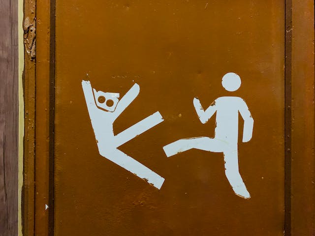 A drawing on a door shows a human figure kicking another. 
