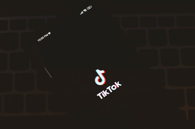 Un ecran negru al telefonului afișează numele și logo-ul TikTok. 