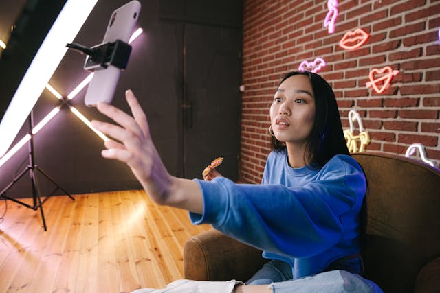 A person recording a video with a phone attached to a ring light.
