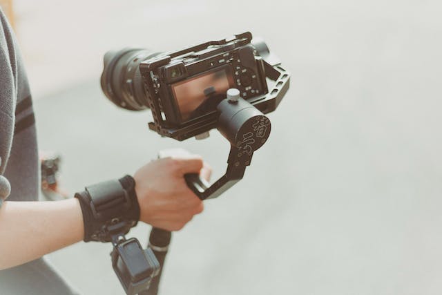 A person holds a black camera and a gimbal.