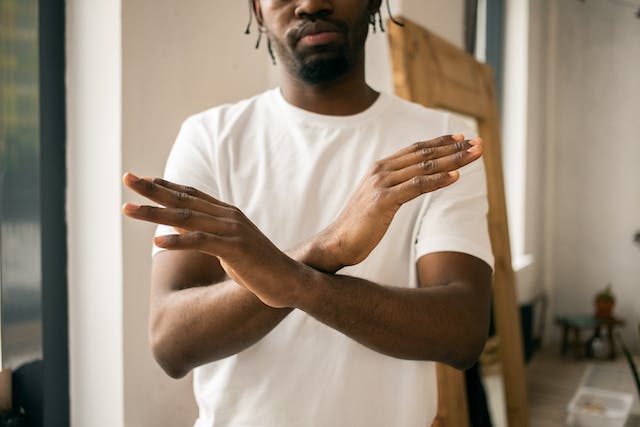 A man demonstrates the stop gesture by crossing his hands. 
