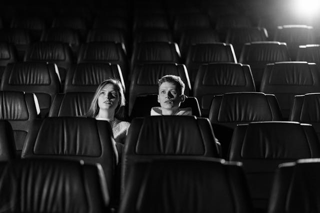 Um casal em um cinema vazio olha para a tela. 