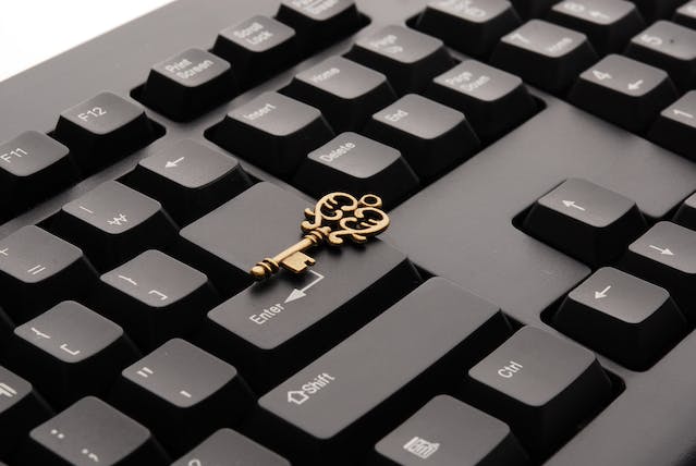 An ornate brass key sits on a computer keyboard. 
