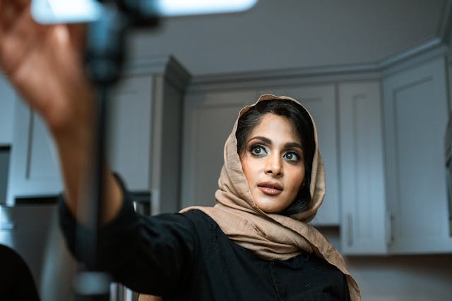 Una mujer con hiyab prepara su cámara para grabar un vídeo.