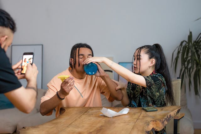 Someone records another person drinking from a jar while another looks on.
