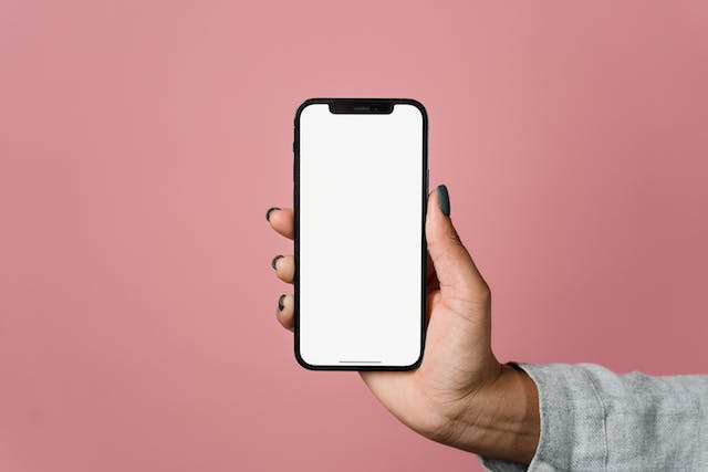 A person holds a phone with a blank, white screen.