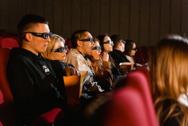 An audience wears 3D glasses at a cinema. 
