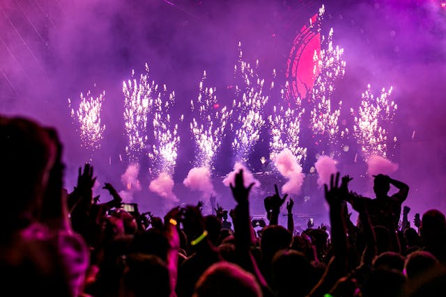 Ein großes Publikum jubelt, als auf der Bühne eines Konzerts ein Feuerwerk gezündet wird. 