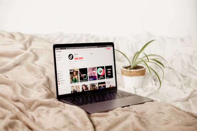 A laptop on a bed with a TikTok profile displayed on the screen.