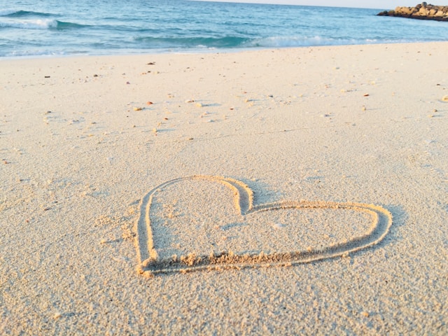 해변의 모래 위에 손으로 그린 하트 모양.