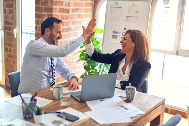 Two co-workers give each other a high-five after a successful audit. 