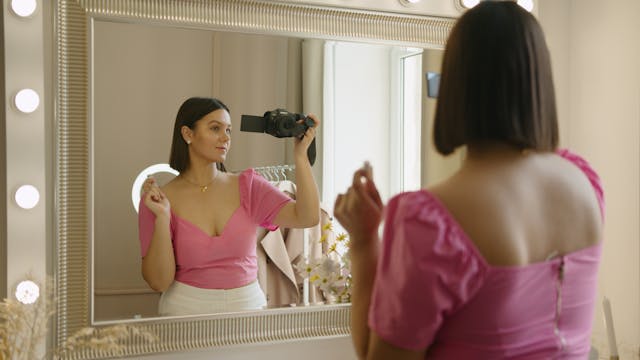 A woman records herself in the mirror.