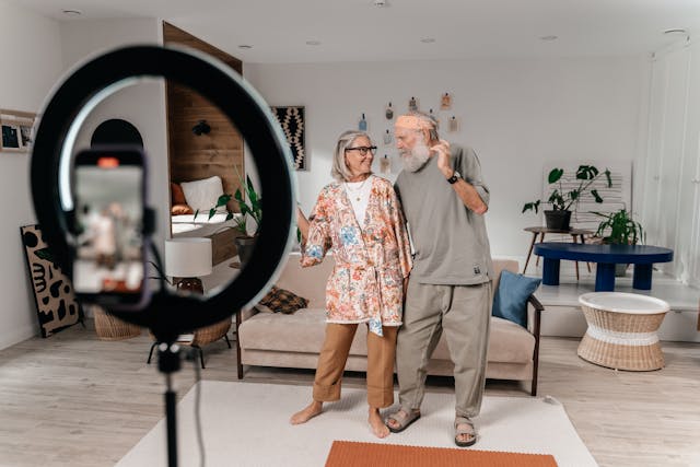 Um casal de idosos dança em frente a uma câmera para seus espectadores AO VIVO no TikTok. 