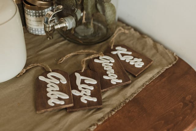 Quatre badges en bois sont posés sur une nappe brune.