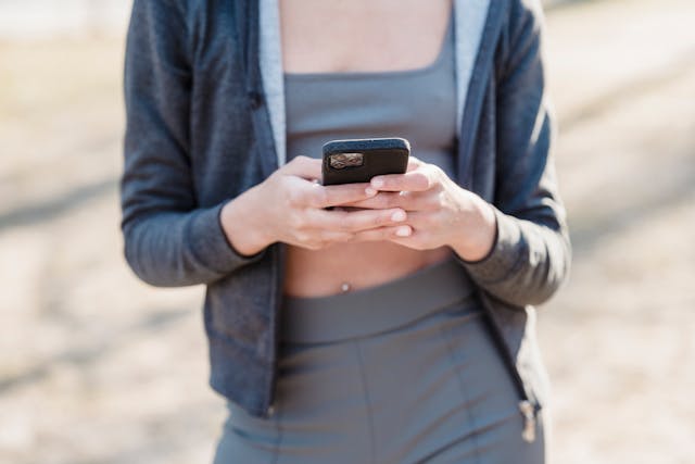 Una mujer vestida de corredora utiliza su teléfono para navegar en TikTok. 