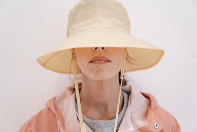 Una donna nasconde la sua identità con un cappello da sole che le copre metà del viso. 