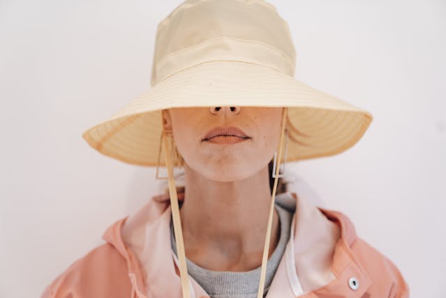 A woman hides her identity with a sun hat covering half her face. 
