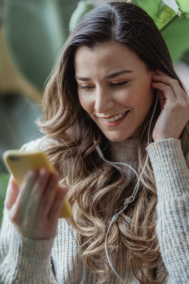 Una mujer utiliza un teléfono con los auriculares conectados.