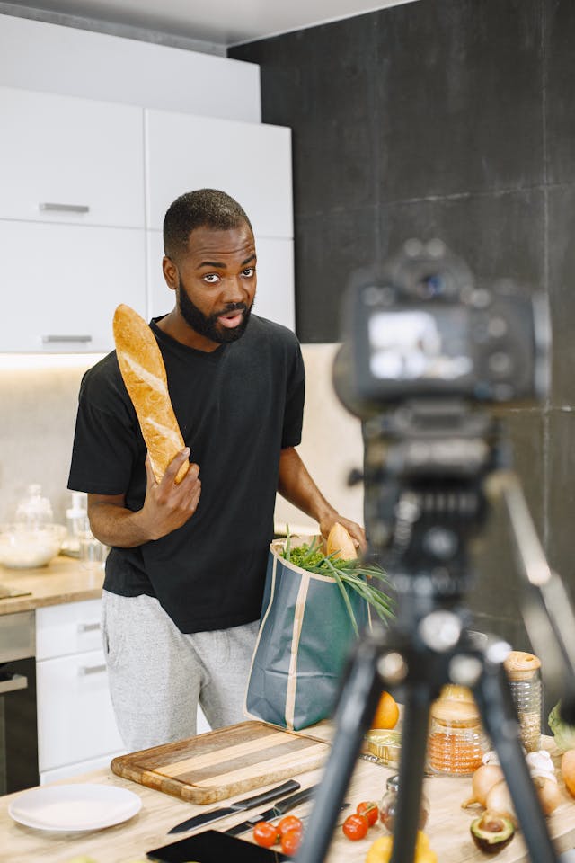 Een man neemt zichzelf op terwijl hij een stokbrood laat zien.