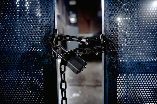 A chain and a padlock secure partially open metal gates. 
