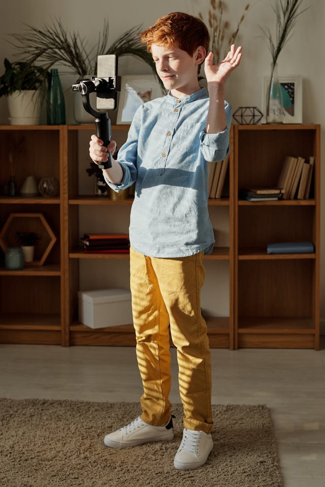 A young boy holds his phone with a selfie stick.