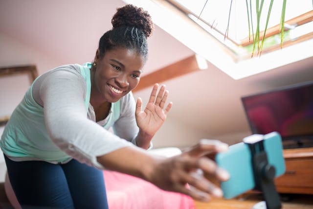 A woman waves to her mounted phone.