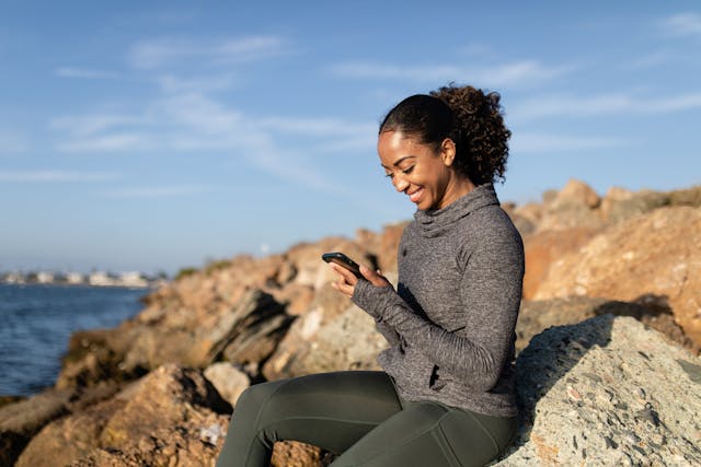 A woman looks at her phone screen and grins.