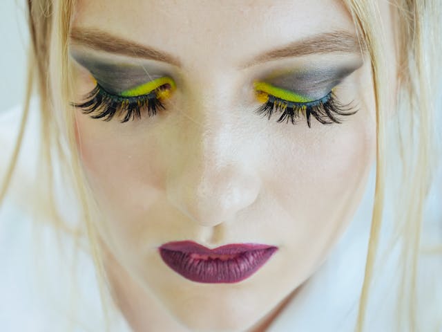 Uma foto em close-up de uma mulher usando maquiagem ousada e colorida.
