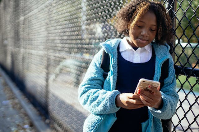 Een jong meisje kijkt naar iets op het scherm van haar mobiele telefoon.