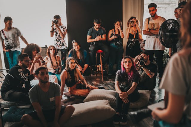 Une foule engagée s'assoit devant un orateur et prend des photos et des vidéos avec son téléphone.