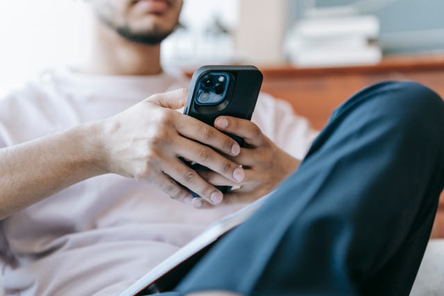 Een man houdt een mobiele telefoon in zijn handen.