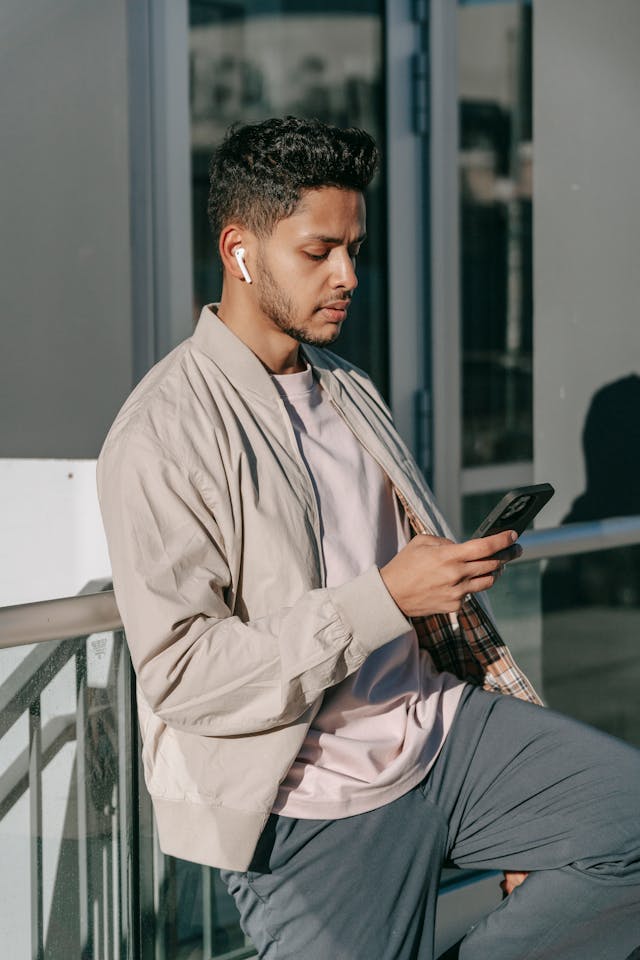 一名戴着 Airpods 的男子正在翻看手机。