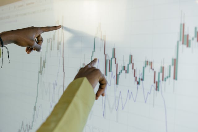 Two people trace the lines on a graph on a giant screen.  
