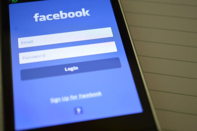 Uma tela de telefone exibe a página de login do Facebook.