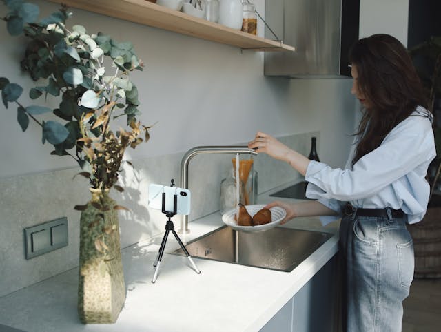 Uma mulher grava a si mesma lavando alimentos.