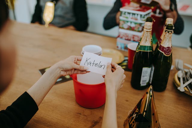 A person holds a white piece of paper with the name “Katelin” printed on it.