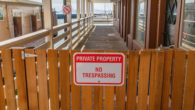 Een houten hek met een rood en wit bord waarop staat: "Privéterrein, verboden toegang.