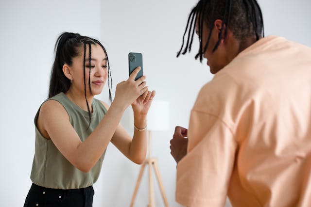 A woman records a man with her cell phone.