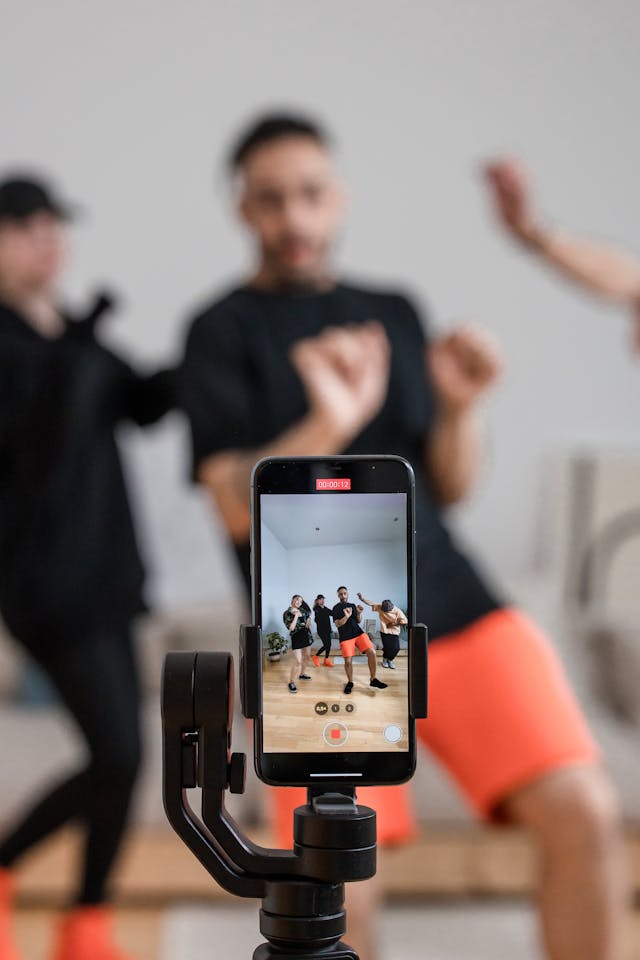 A group of people use a cellphone on a tripod to record themselves dancing.
