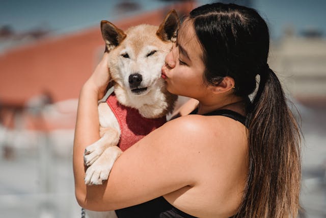 A woman kisses her dog.