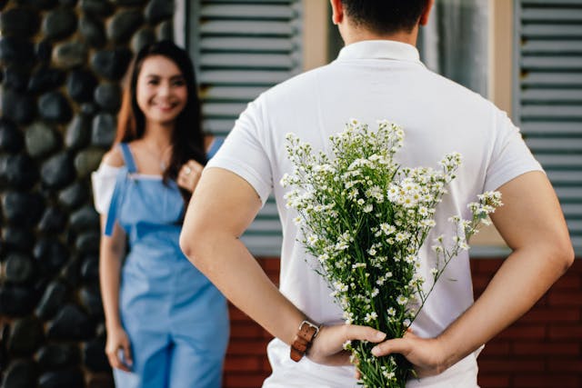 A man meets a woman holding flowers.