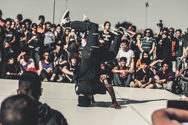 Uma grande multidão se reúne em torno de um dançarino de hip-hop. 